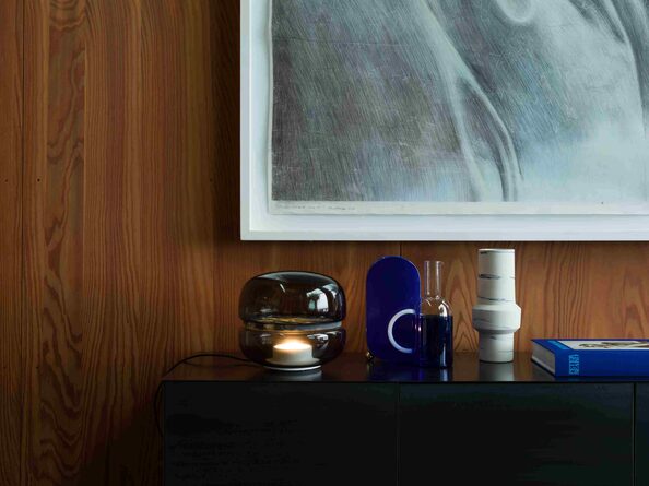 Leuchtende Macaron neben Vasen auf einem Sideboard vor einer Holzvertäfelung